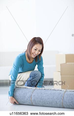 Stock Image - Woman carrying rug. Fotosearch