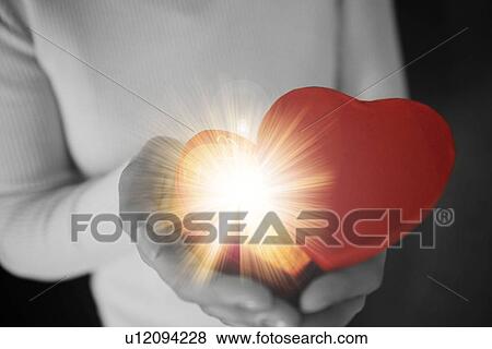 Stock Photo - Woman holding a glowing heart shaped box. Fotosearch