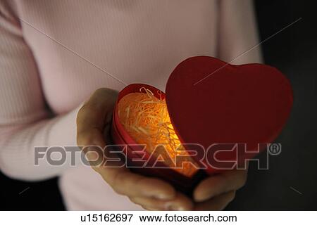 Woman holding a glowing heart shaped box View Large Photo Image Stock Photo - Woman holding a glowing heart shaped box. Fotosearch
