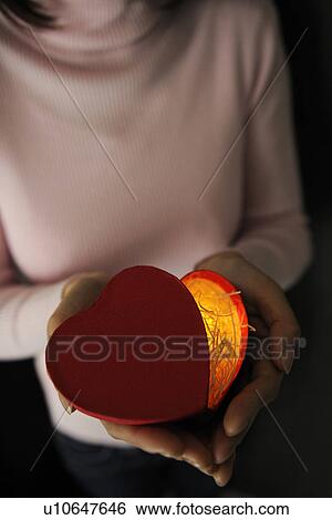 Woman holding a glowing heart shaped box View Large Photo Image Stock Photograph - Woman holding a glowing heart shaped box. Fotosearch