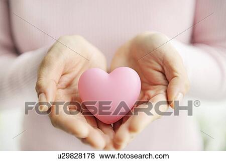 Woman holding a pink heart View Large Photo Image Stock Photo - Woman holding a pink heart. Fotosearch