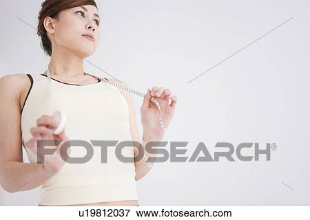 Woman holding a tape measure View Large Photo Image Stock Photo - Woman holding a tape measure. Fotosearch