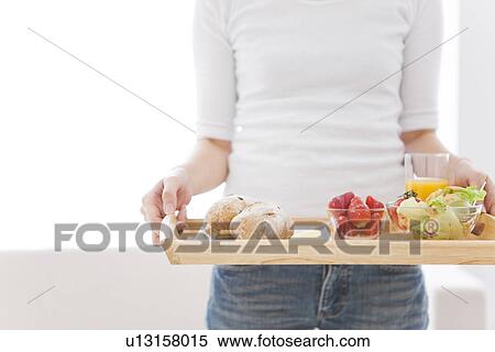 Woman holding tray with a meal of salad, strawberries and bread rolls and a glass of juice View Large Photo Image Stock Photography - Woman holding tray with a meal of salad, strawberries and bread rolls and a glass of juice. Fotosearch