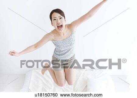 Stock Image - Woman jumping on bed. Fotosearch