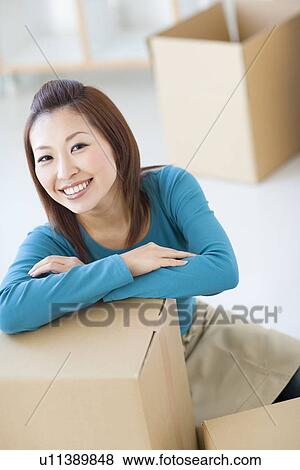 Stock Photo - Woman leaning on cardboard box. Fotosearch