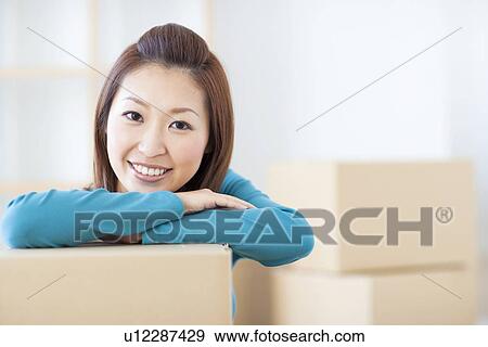 Stock Photo - Woman leaning on cardboard box. Fotosearch