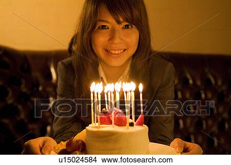 Woman leaning over to blow out the candles on her birthday cake View Large Photo Image Picture - Woman leaning over to blow out the candles on her birthday cake. Fotosearch