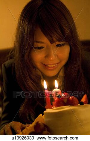 Woman leaning over to blow out the candles on her birthday cake View Large Photo Image Stock Photo - Woman leaning over to blow out the candles on her birthday cake. Fotosearch