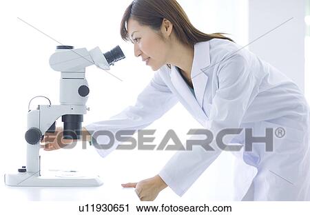 Stock Image - Woman looking through microscope. Fotosearch