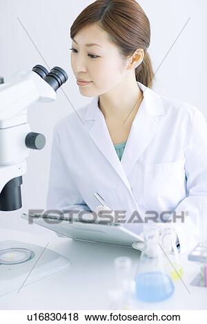 Stock Photo - Woman looking through microscope. Fotosearch