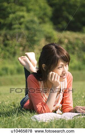 Woman lying on grass reading a book View Large Photo Image Stock Photo - Woman lying on grass reading a book. Fotosearch