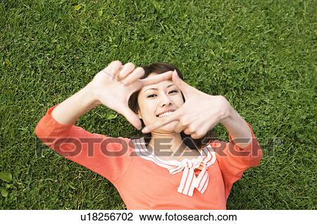 Stock Image - Woman lying on grass. Fotosearch