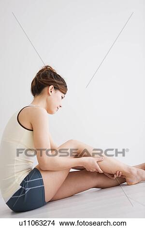 Picture - Woman massaging her leg. Fotosearch
