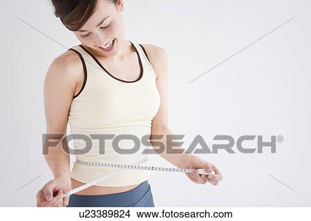 Picture - Woman measuring her waist. Fotosearch