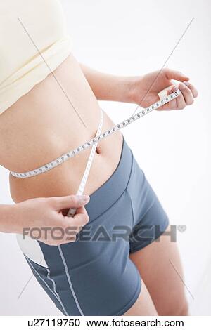 Stock Image - Woman measuring her waist. Fotosearch