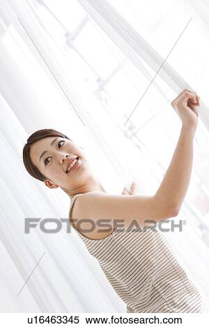 Stock Photography - Woman opening curtain. Fotosearch