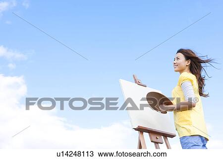 Stock Image - Woman painting in a field. Fotosearch