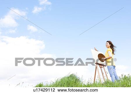 Stock Image - Woman painting in a field. Fotosearch