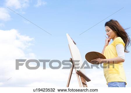 Woman painting in a field View Large Photo Image Stock Image - Woman painting in a field. Fotosearch