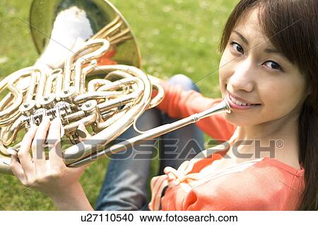 Woman playing a French horn View Large Photo Image Stock Image - Woman playing a French horn. Fotosearch