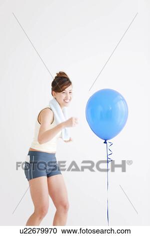 Stock Image - Woman punching a balloon. Fotosearch