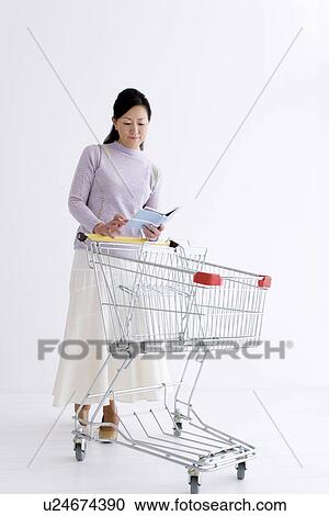 Woman pushing a shopping cart and looking through a notebook View Large Photo Image Stock Image - Woman pushing a shopping cart and looking through a notebook. Fotosearch