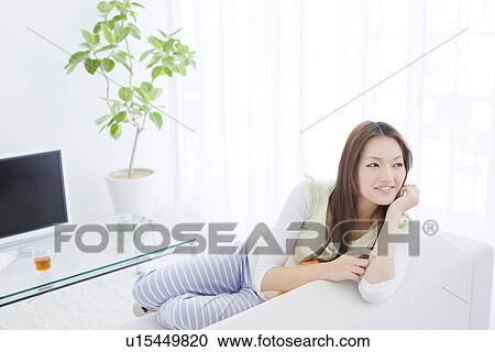 Stock Image - Woman relaxing in living room. Fotosearch