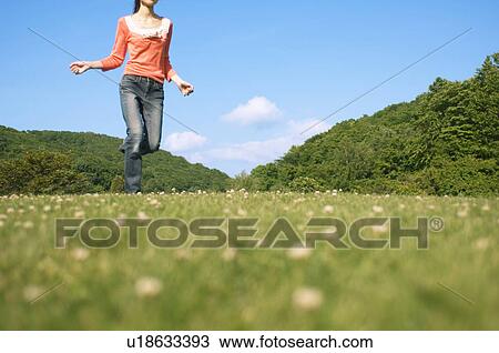 Stock Image - Woman running in a field. Fotosearch