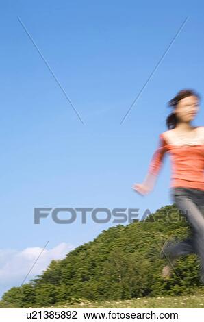 Stock Image - Woman running in a field. Fotosearch