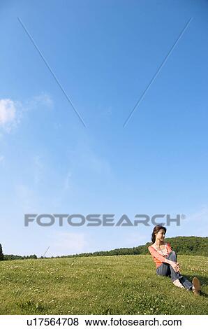 Stock Photo - Woman sitting in a field. Fotosearch