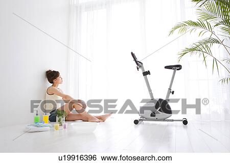 Woman sitting near exercise bike View Large Photo Image Stock Photograph - Woman sitting near exercise bike. Fotosearch