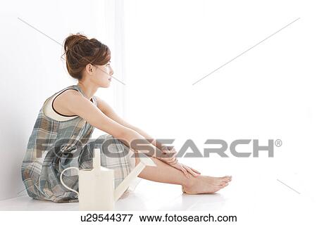 Stock Photo - Woman sitting next to watering can. Fotosearch