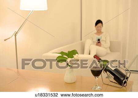 Woman sitting on a sofa using a mobile phone View Large Photo Image Stock Image - Woman sitting on a sofa using a mobile phone. Fotosearch