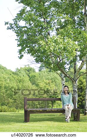 Woman sitting on bench in park View Large Photo Image Stock Photograph - Woman sitting on bench in park. Fotosearch