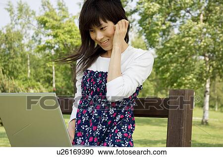 Woman sitting on bench in park with laptop View Large Photo Image Stock Image - Woman sitting on bench in park with laptop. Fotosearch