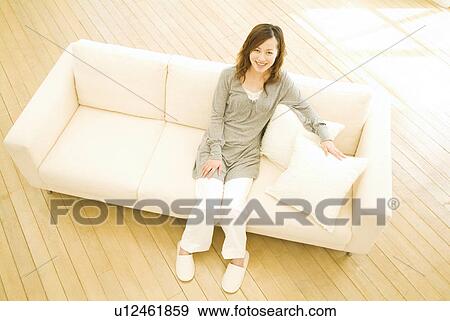 Stock Photo - Woman sitting on sofa. Fotosearch