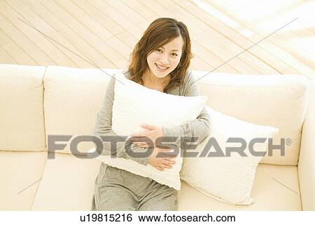 Stock Photograph - Woman sitting on sofa. Fotosearch