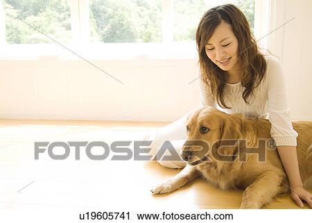 Stock Image - Woman sitting on the floor with her dog. Fotosearch