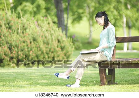 Woman sitting reading on park bench View Large Photo Image Stock Image - Woman sitting reading on park bench. Fotosearch