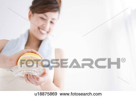 Stock Photo - Woman squeezing grapefruit juice. Fotosearch
