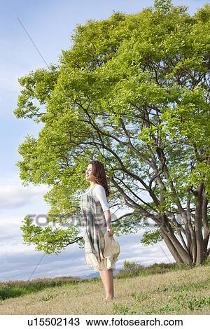 Stock Image - Woman standing in a field. Fotosearch