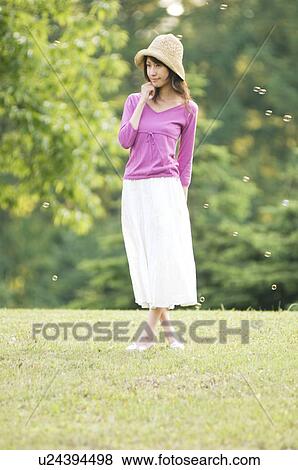 Woman standing in a field with bubbles floating around her View Large Photo Image Stock Photo - Woman standing in a field with bubbles floating around her. Fotosearch