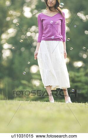 Woman standing in a field with bubbles floating around her View Large Photo Image Stock Photography - Woman standing in a field with bubbles floating around her. Fotosearch