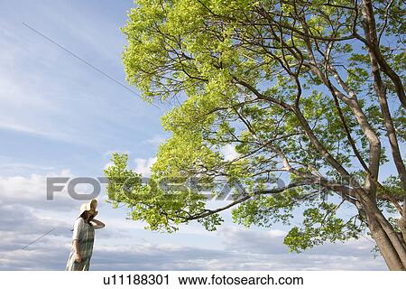 Woman standing next to a tree View Large Photo Image Stock Image - Woman standing next to a tree. Fotosearch