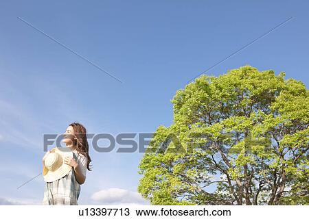 Woman standing next to a tree View Large Photo Image Stock Image - Woman standing next to a tree. Fotosearch