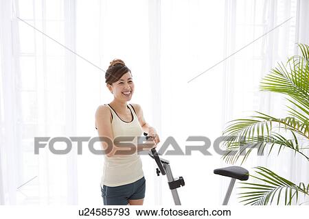 Woman standing next to an exercise bike View Large Photo Image Stock Image - Woman standing next to an exercise bike. Fotosearch
