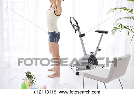 Woman standing next to an exercise bike View Large Photo Image Stock Photography - Woman standing next to an exercise bike. Fotosearch