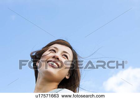 Stock Image - Woman standing under a blue sky. Fotosearch