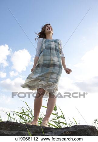 Stock Image - Woman standing under a blue sky. Fotosearch