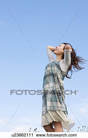 Stock Image - Woman standing under a blue sky. Fotosearch